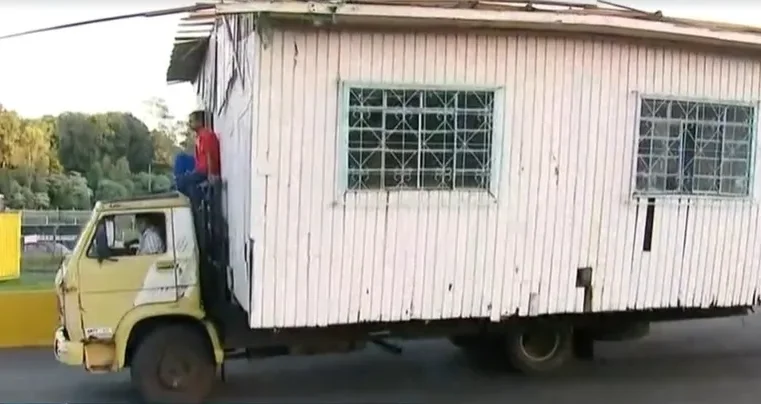 Caminhão transporta casa de madeira com homem no teto do veículo em SC